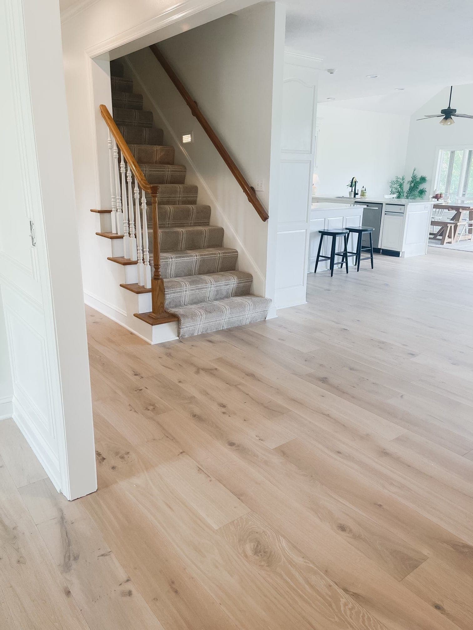 Sunlit open-concept home with wide-plank hardwood floors and a custom stair runner